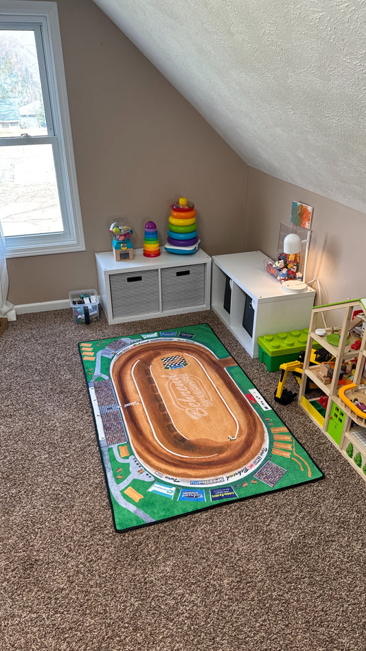 Children's playroom with toys and a large Dirt Track rug on the floor.