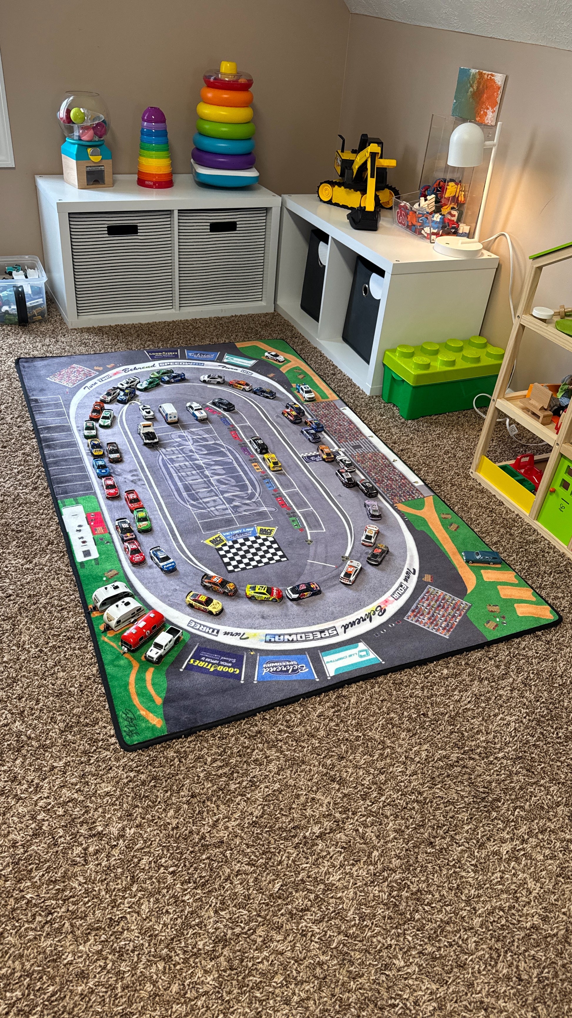 Children's playroom with a large race track rug and toy cars.