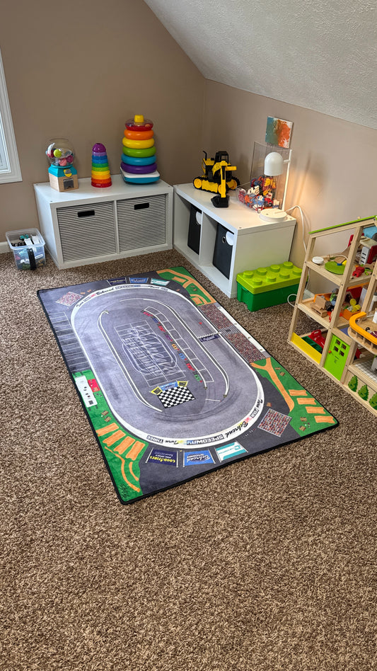 Children's playroom with a large race track rug on the floor.