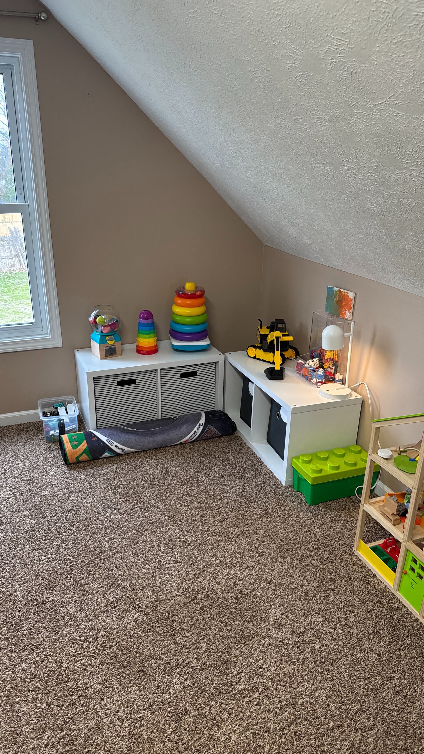 Rolled carpet stored along toy shelf